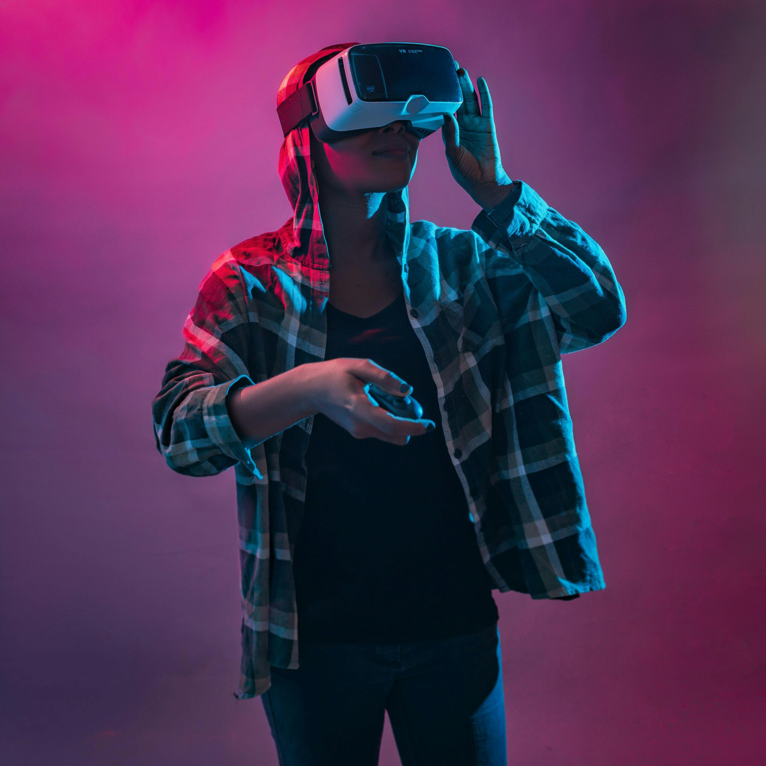 A woman wearing a VR headset and plaid shirt explores virtual reality indoors with vibrant lighting.