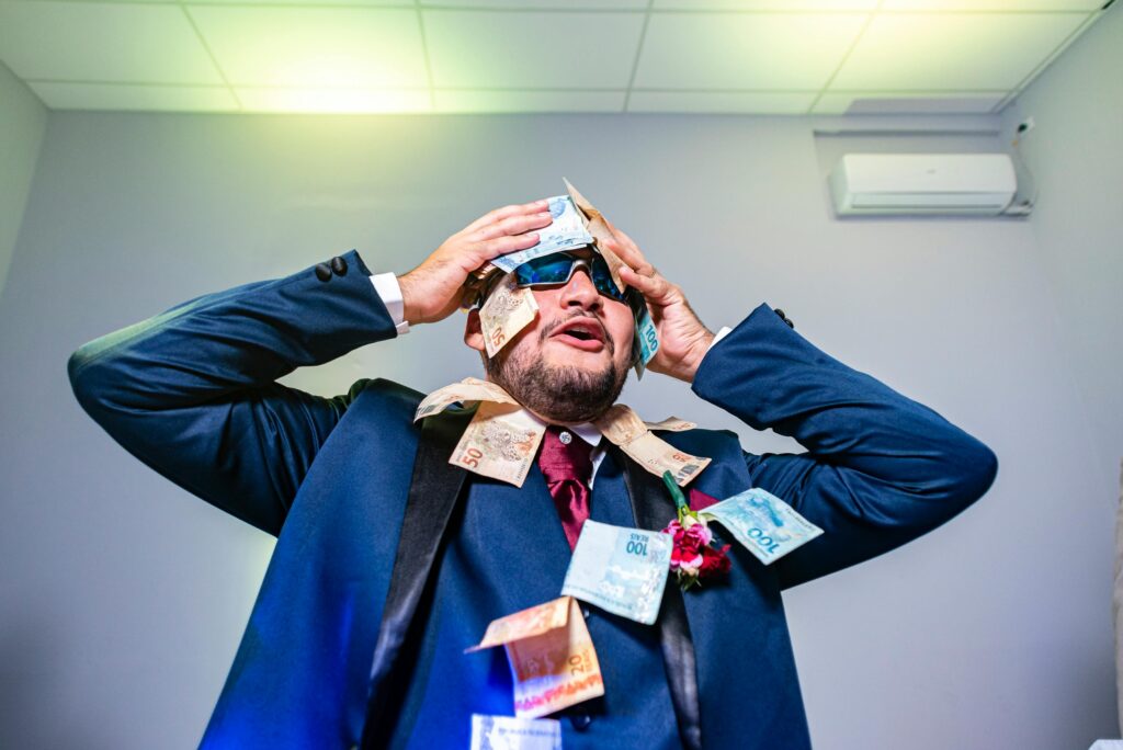 A joyful man in a suit with banknotes on him, celebrating indoors.