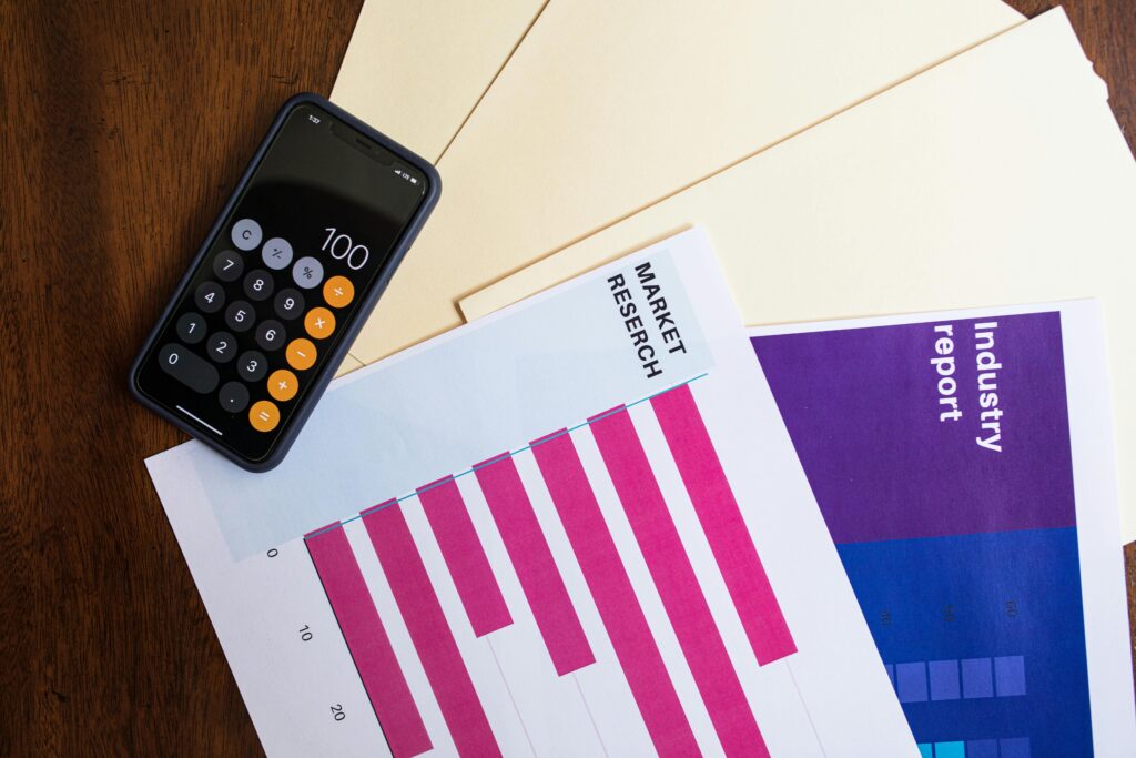 Flat lay of smartphone and market research papers on wooden table for business analysis.